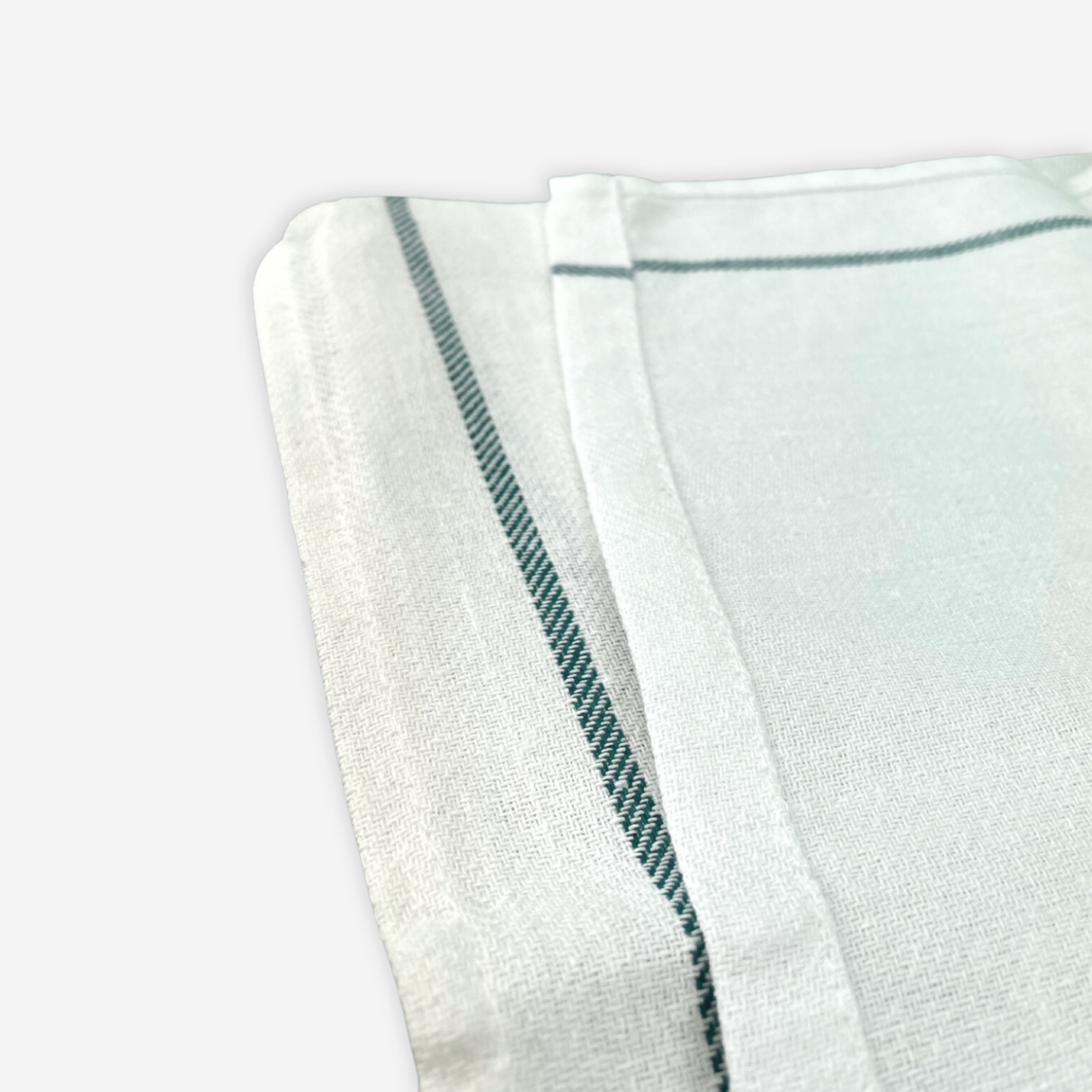 Close up view on a white bleached kitchen towel with green side on the borders, folded on a white background.