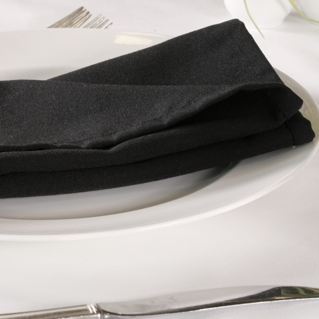 Black lieberspun napkins folded on a plate in a dressed up restaurant table