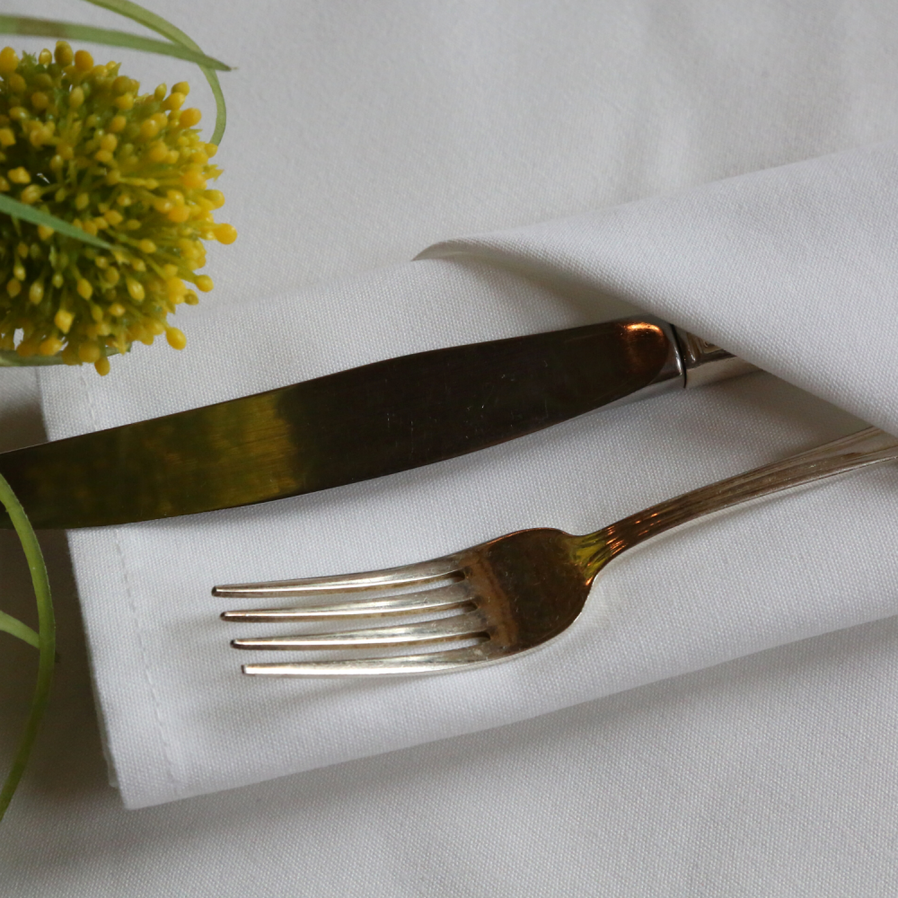 Silver cutlery placed on a white lieberspun napkin.