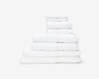 White hotel towels folded and placed on top of each other to form a pile.