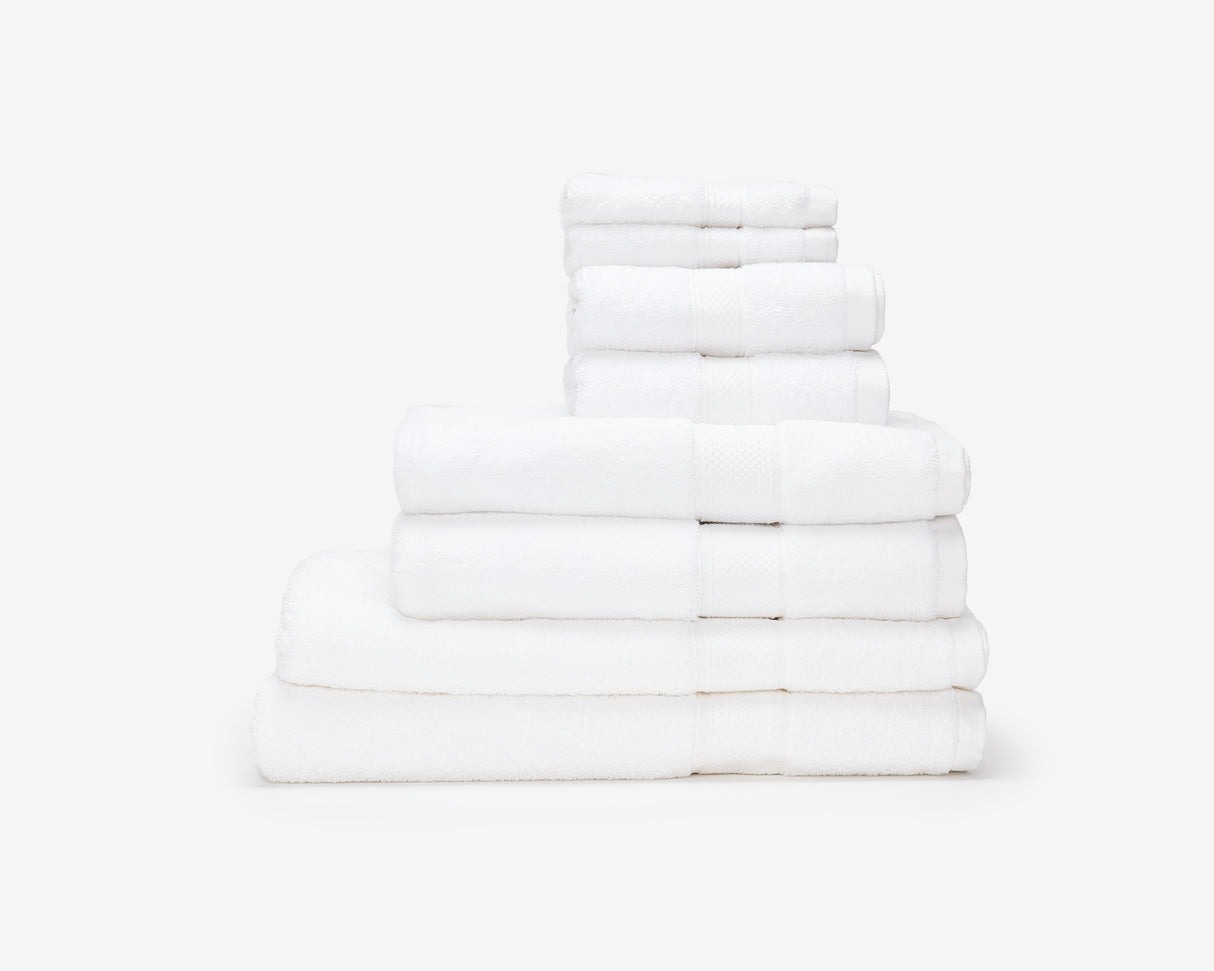White hotel towels folded and placed on top of each other to form a pile.