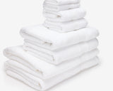 White hotel towels from different sizes folded and placed on top of each other to form a pile.