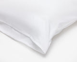 Corner of a hotel pillow featuring a white pillow protector with flap