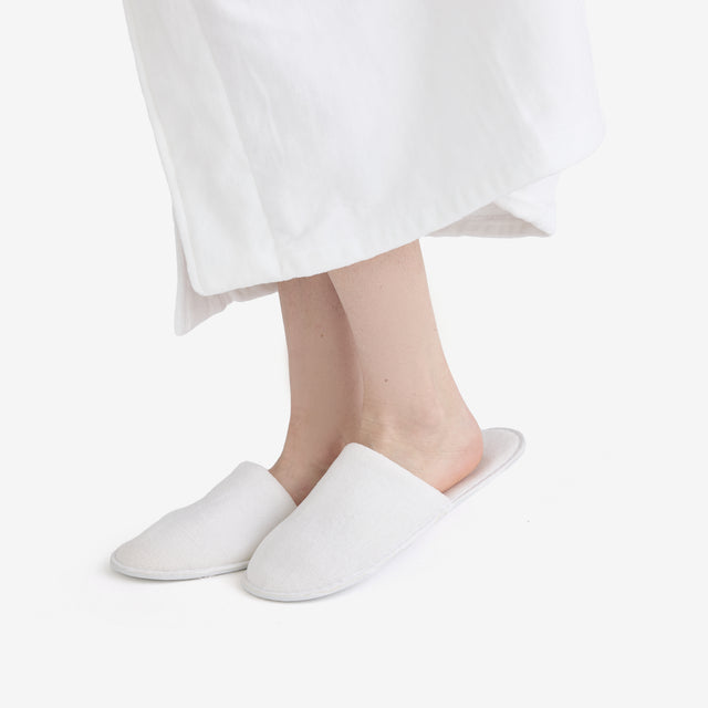 White closed toe slippers, close up view on the product worn by a client.