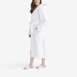 Women wearing a white hotel bathrobe with a hood and white open slippers.