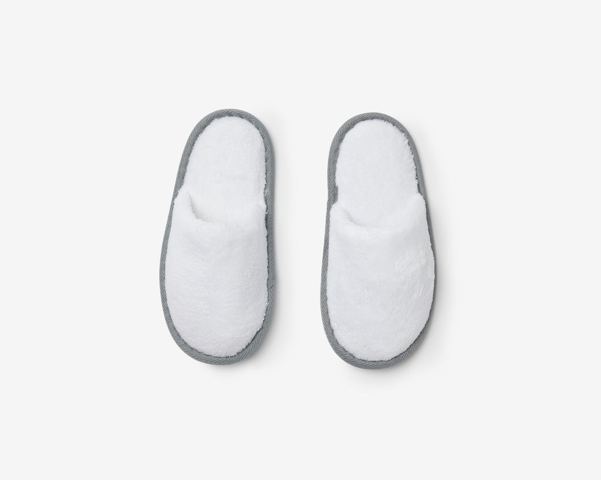 White closed toe kids slippers with a grey sole, view from above.