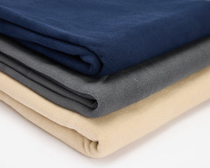 Three polar fleece blankets folded and placed in a pile, a blue, grey and beige.