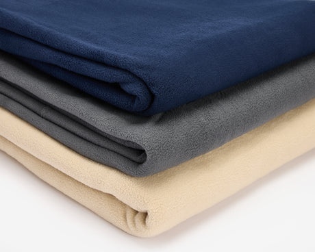 Three polar fleece blankets folded and placed in a pile, a blue, grey and beige.