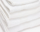 Folded white hotel towel placed on top of each other to form a pile.