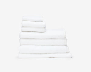 Folded white hotel towel placed on top of each other to create a pile.