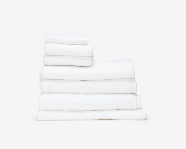 Folded white hotel towel placed on top of each other to create a pile.