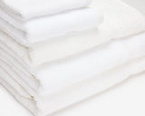 Folded white hotel towels placed on top of each other to form a pile.