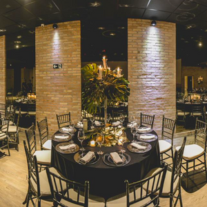 Restaurant room featuring a dressed up table with a black lieberspun tablecloth and white napkins.